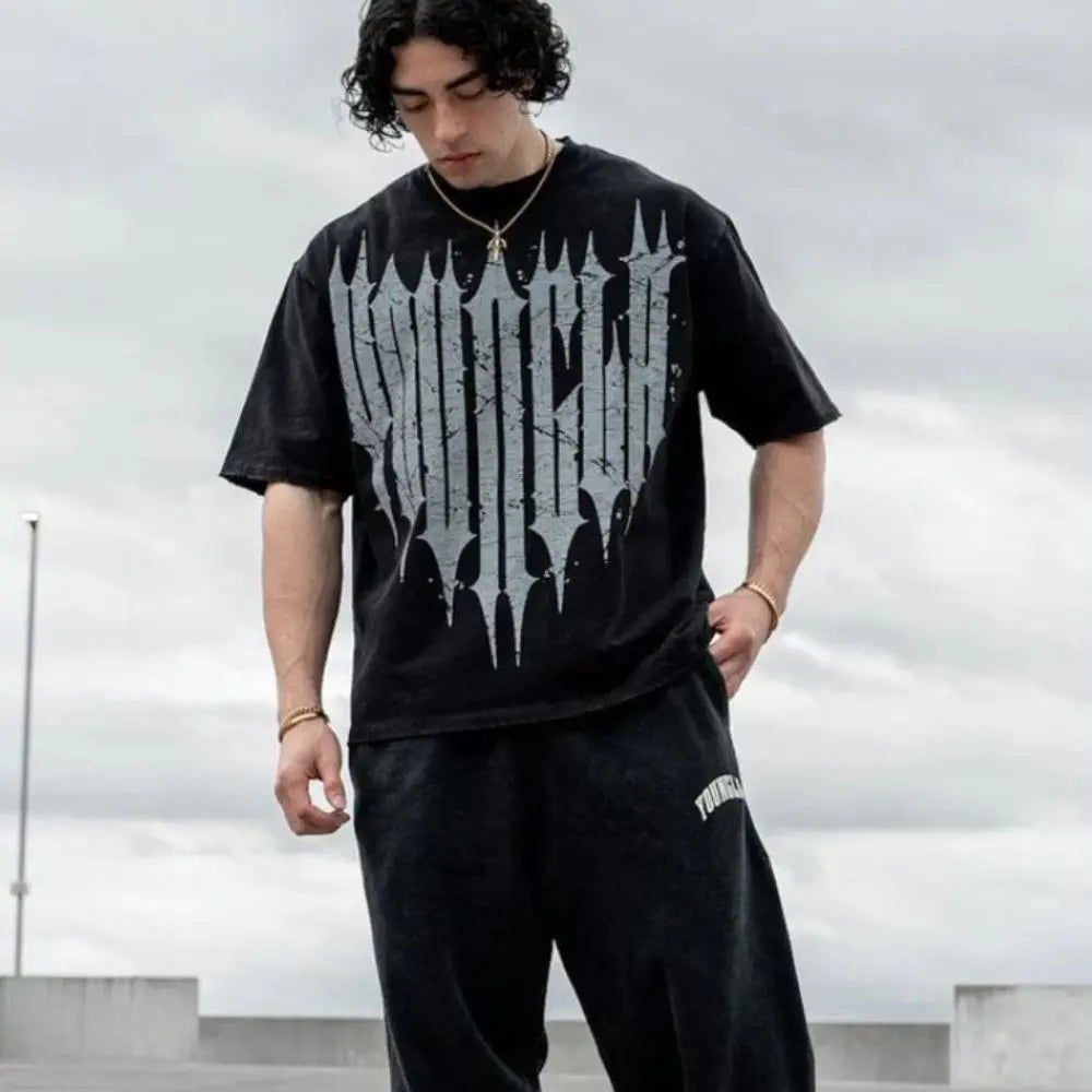 Young man wearing a stylish black graphic t-shirt with a bold design, showcasing modern streetwear fashion.